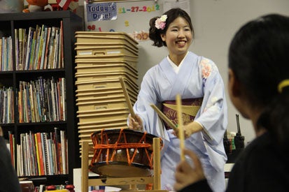 woman in kimono demonstrating japanese drum for students