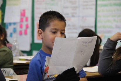 male student reading from a folded booklet